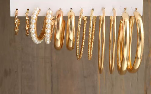 Load image 1 in gallery view. Collection of gold hoop earrings on a white strip against a gray background